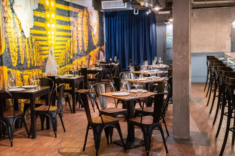 Wooden tables and dark chairs beside a colourful wall mural at Coal by Corks Out in SS15, Subang Jaya.